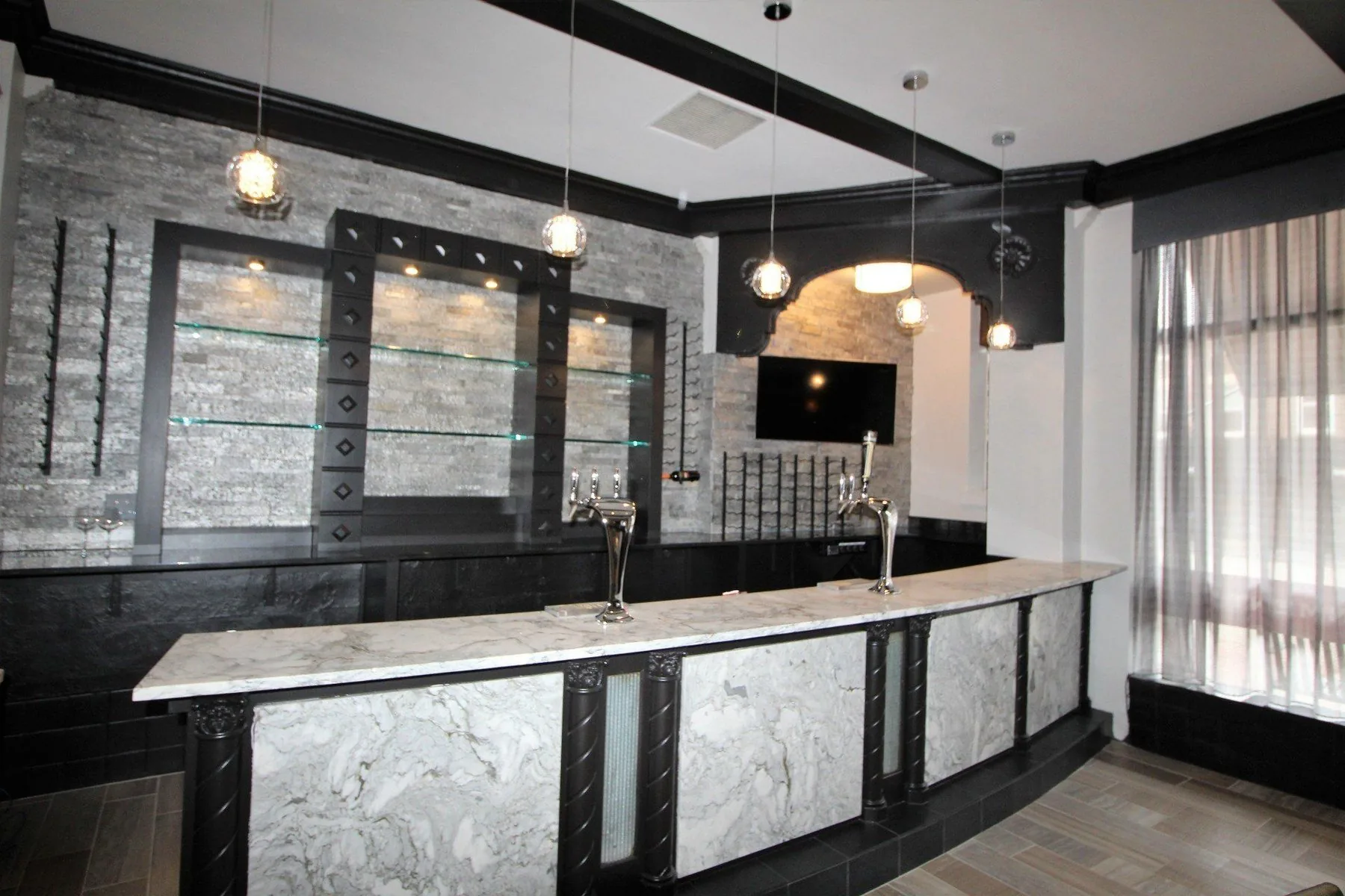 Finished basement bar with marble counter, stone wall and pendant lighting