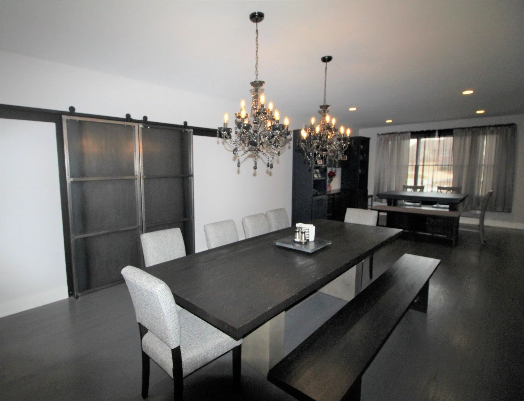 Dining room designed by Fredenhagen with dark table, chandeliers and sliding steel doors