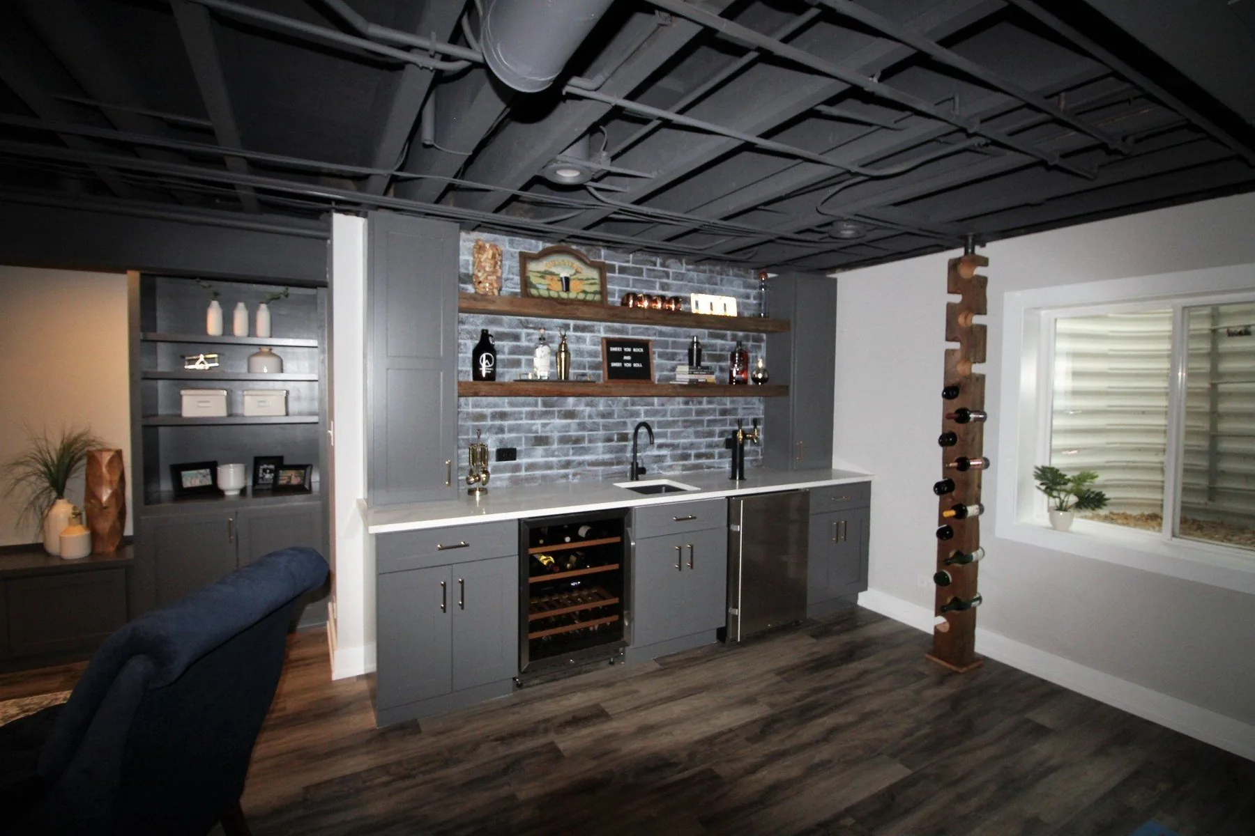Basement home bar with whitewashed brick, floating shelves and wine fridge