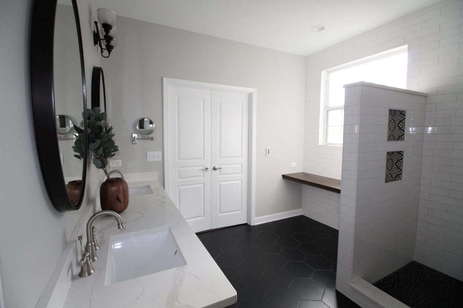 Bathroom remodel with black hexagon tile floor and walk-in subway tile shower